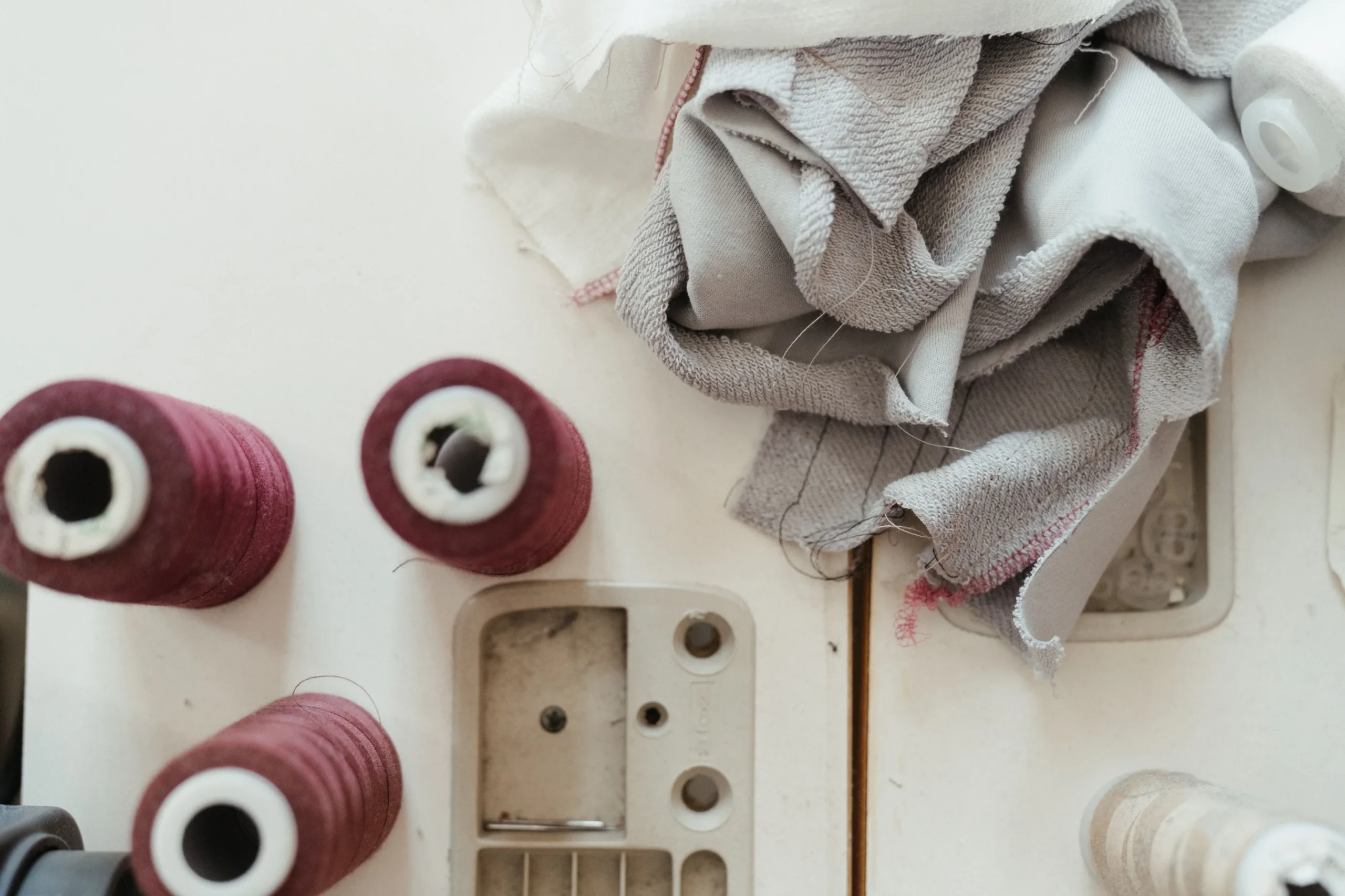 Polyester vs cotton fabric comparison with textile samples and sewing thread in an apparel production setting