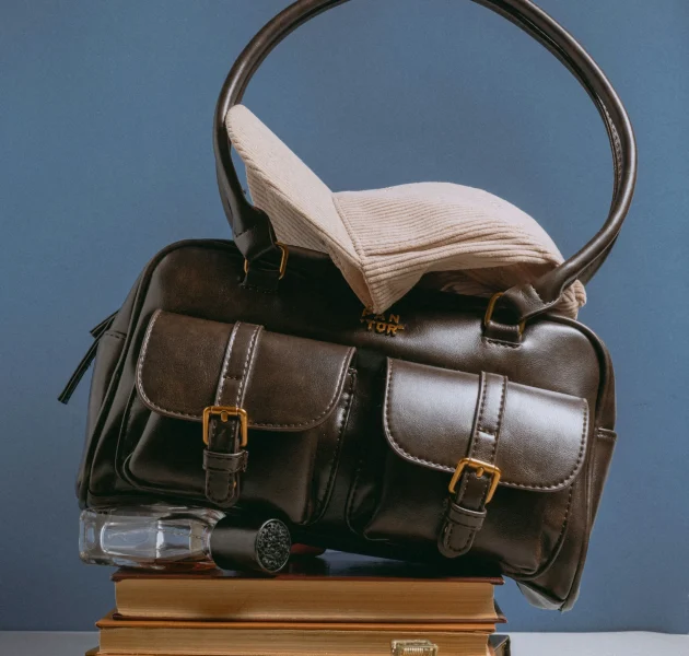Dark brown leather travel bag with front buckle pockets and sturdy handles, crafted by a Duffle Bag Manufacturer for USA fashion and travel brands.